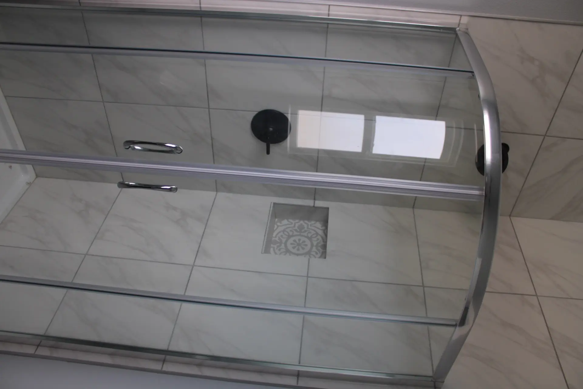 Living room viewed from the kitchen with clean contemporary lines, neutral furnishing tones, and natural light flooding through large coastal windows