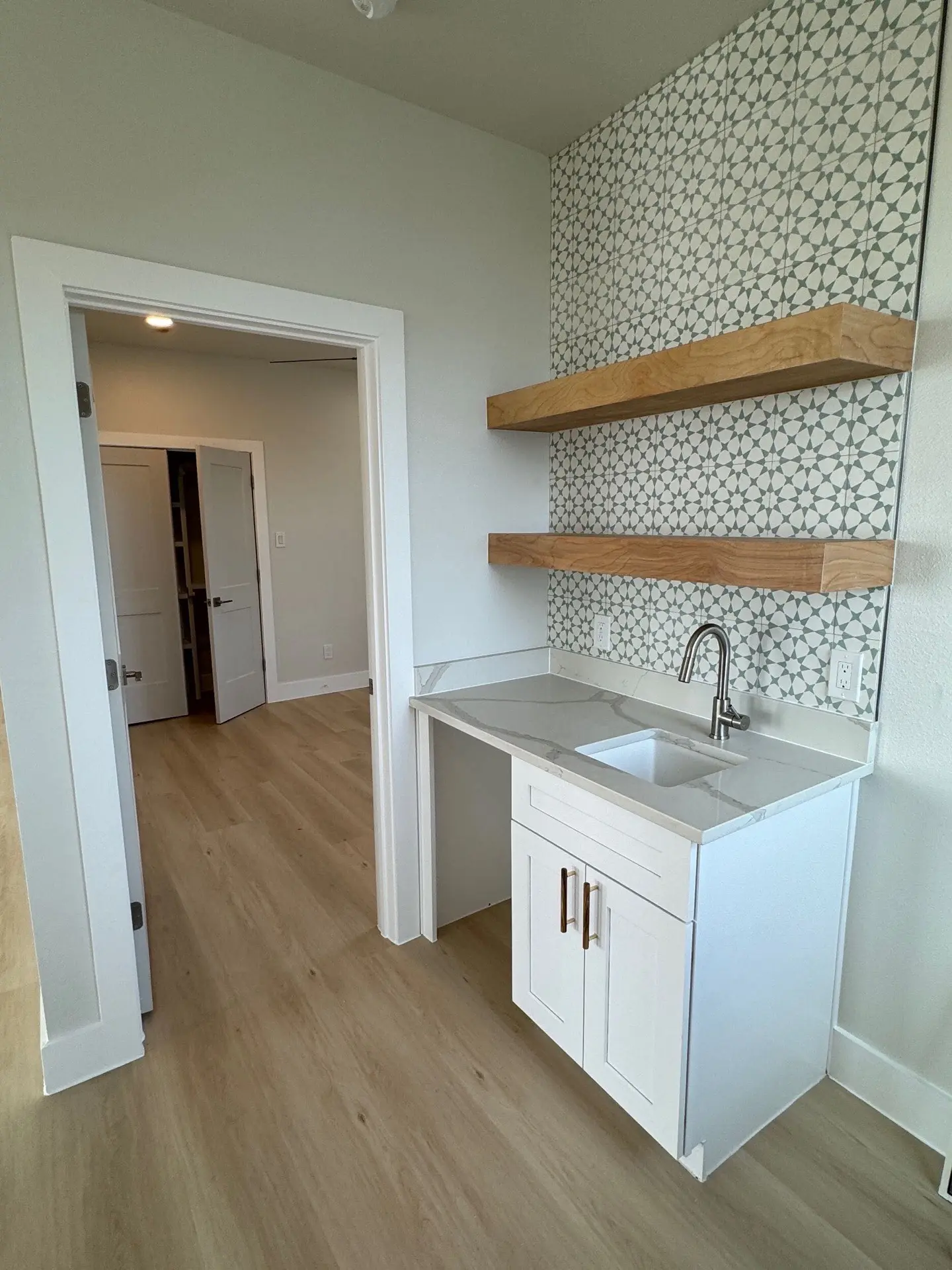 Kitchen sink area with window overlooking the Gulf, white shaker cabinets below, and brass faucet fixture