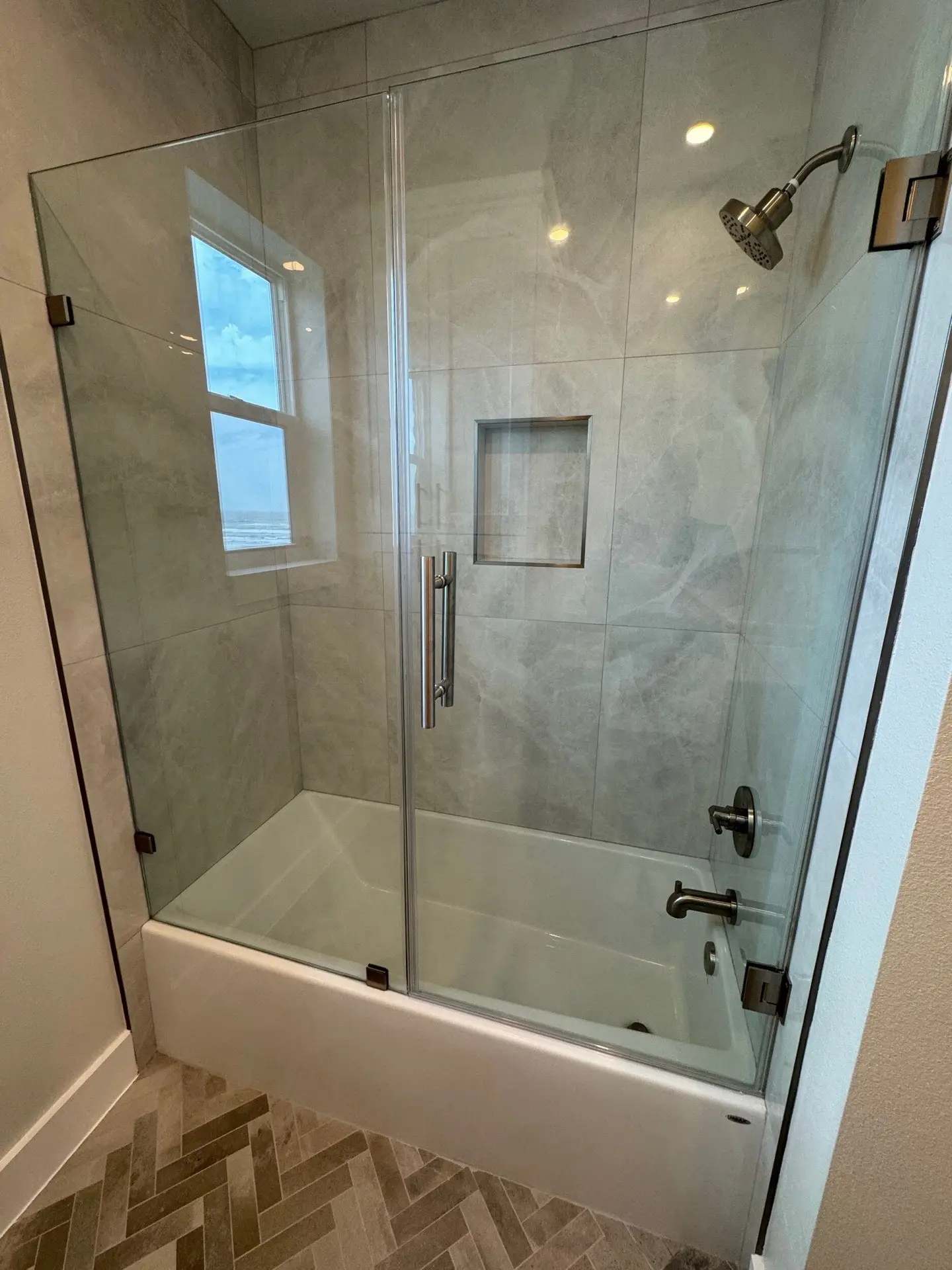 Secondary bathroom featuring coastal blue-gray vanity with marble countertop, brass hardware, and hexagonal floor tile