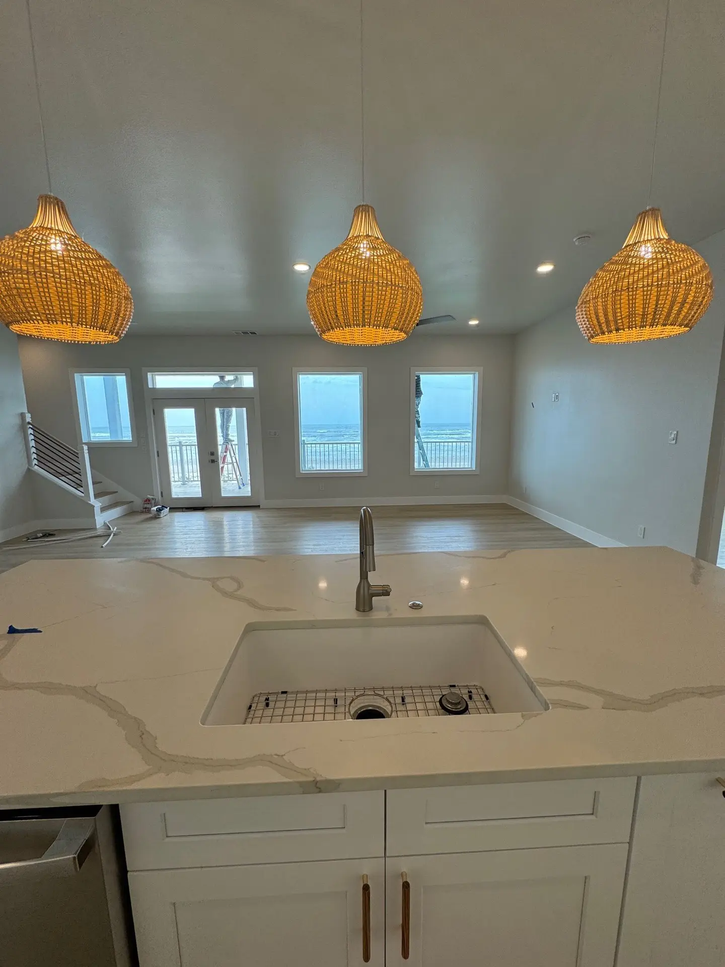 Fourth bathroom vanity detail showing marble countertop edge profile, brass cabinet pulls, and soft coastal color tones