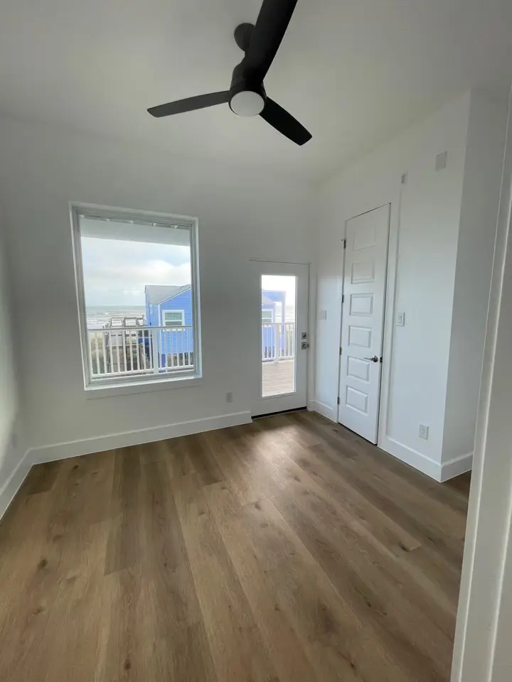 Dining area between the kitchen and living spaces with gulf-facing windows and modern coastal light fixture overhead