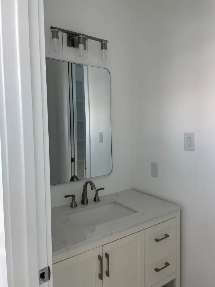 Spa-like master bathroom featuring a jetted soaking tub, floor-to-ceiling marble shower walls, and navy blue double vanity with gold fixtures