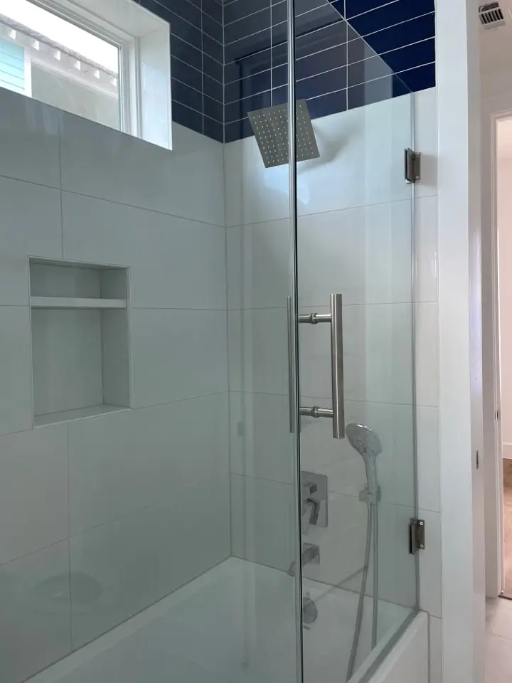 Walk-in marble shower with frameless glass enclosure, rain showerhead, and gold brass shower fixtures in the master bathroom