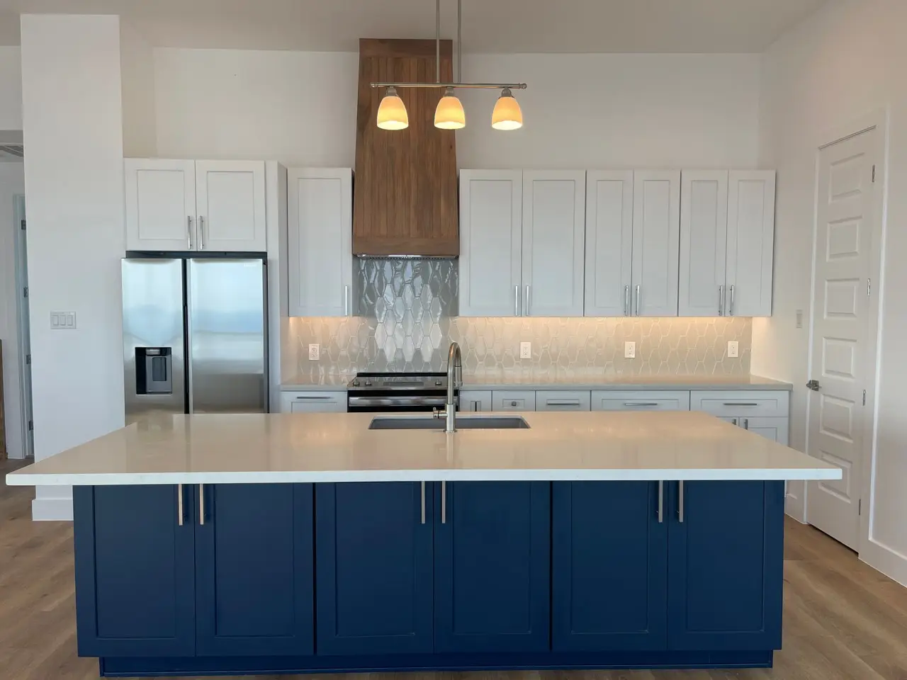Architectural detail of the black metal stair railing and wood tread connection with the two-story great room visible beyond