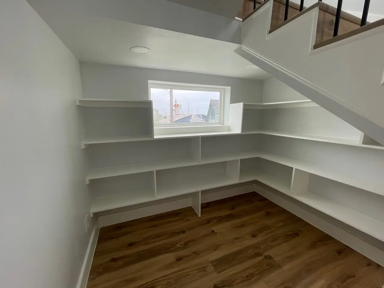 Kitchen and dining area bathed in natural light from floor-to-ceiling windows with clean coastal finishes and modern pendant lighting