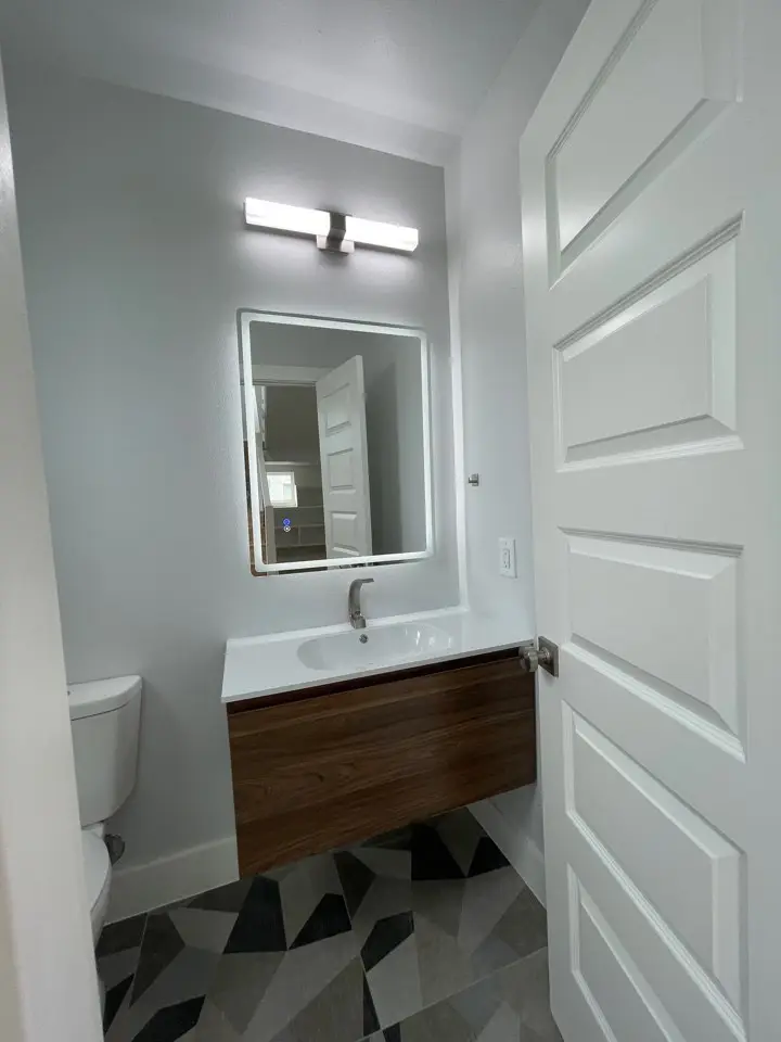 Bathroom with modern fixtures and clean coastal finishes complementing the light wood-look flooring found throughout 227 Gulf Drive