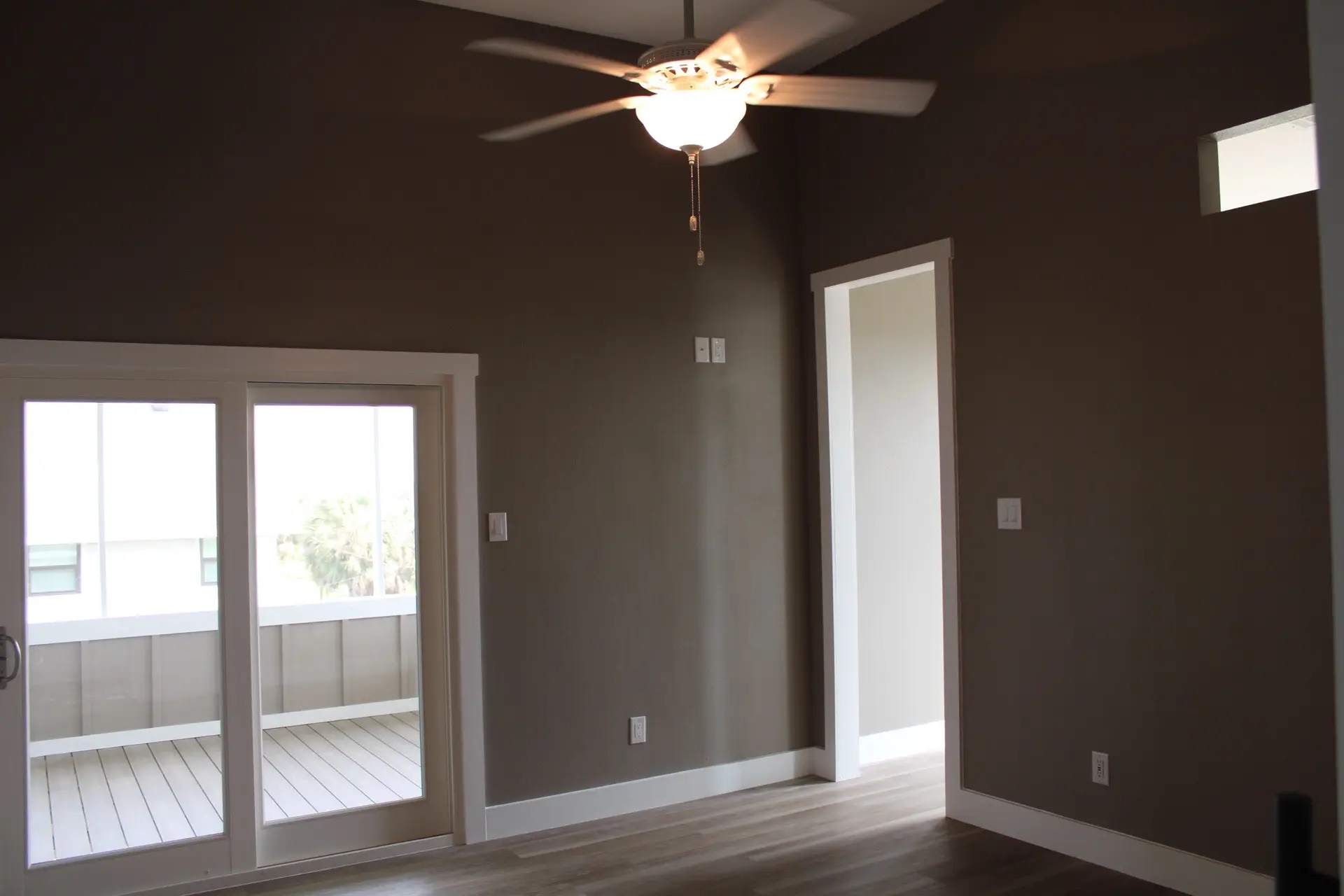 Master bedroom with French sliding doors opening to the covered deck, dark warm brown accent wall, and LVP wood-look flooring at 27 Laguna