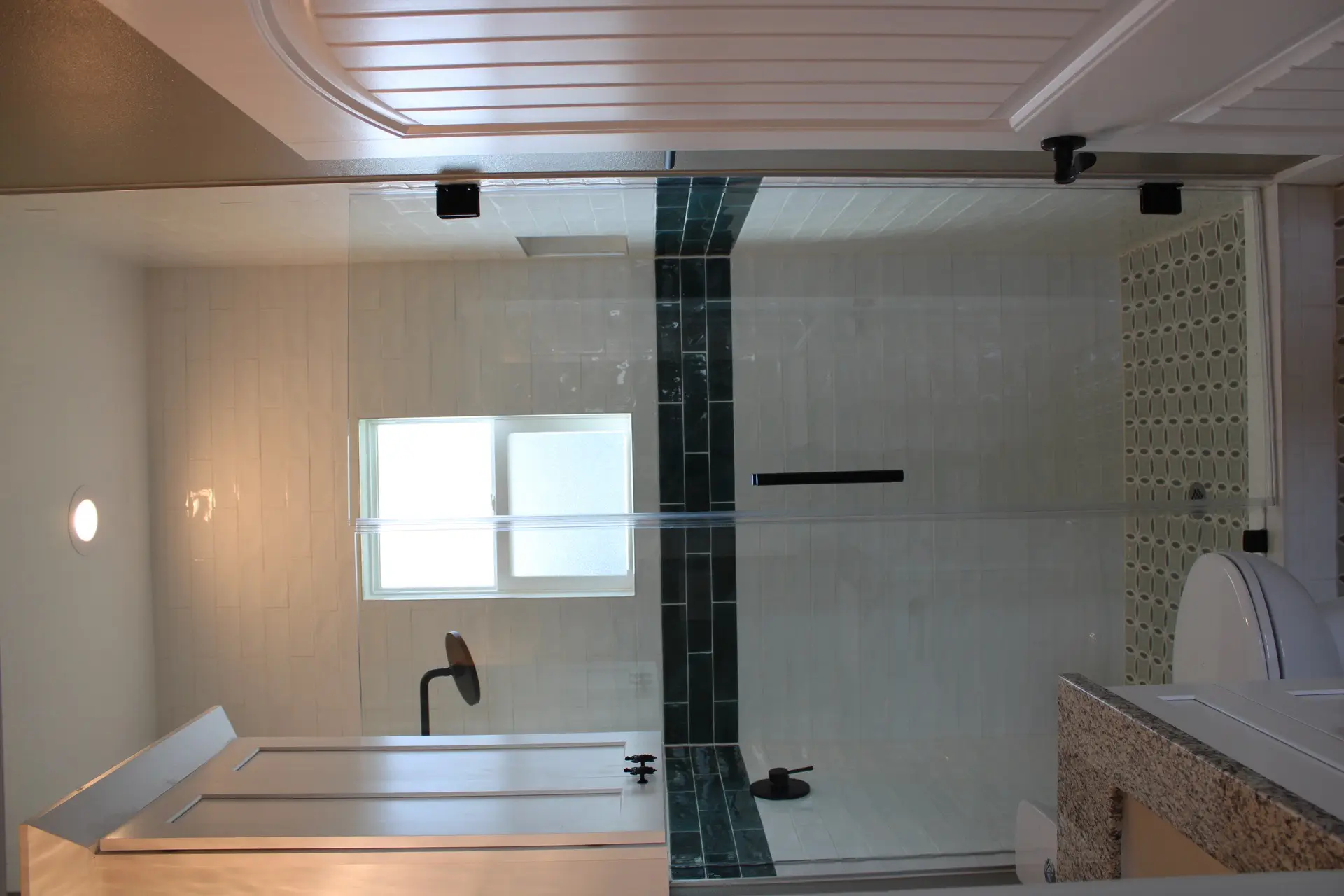 Kitchen sink area with granite countertop, black matte faucet fixture, and window overlooking the palm-lined exterior of the cottage