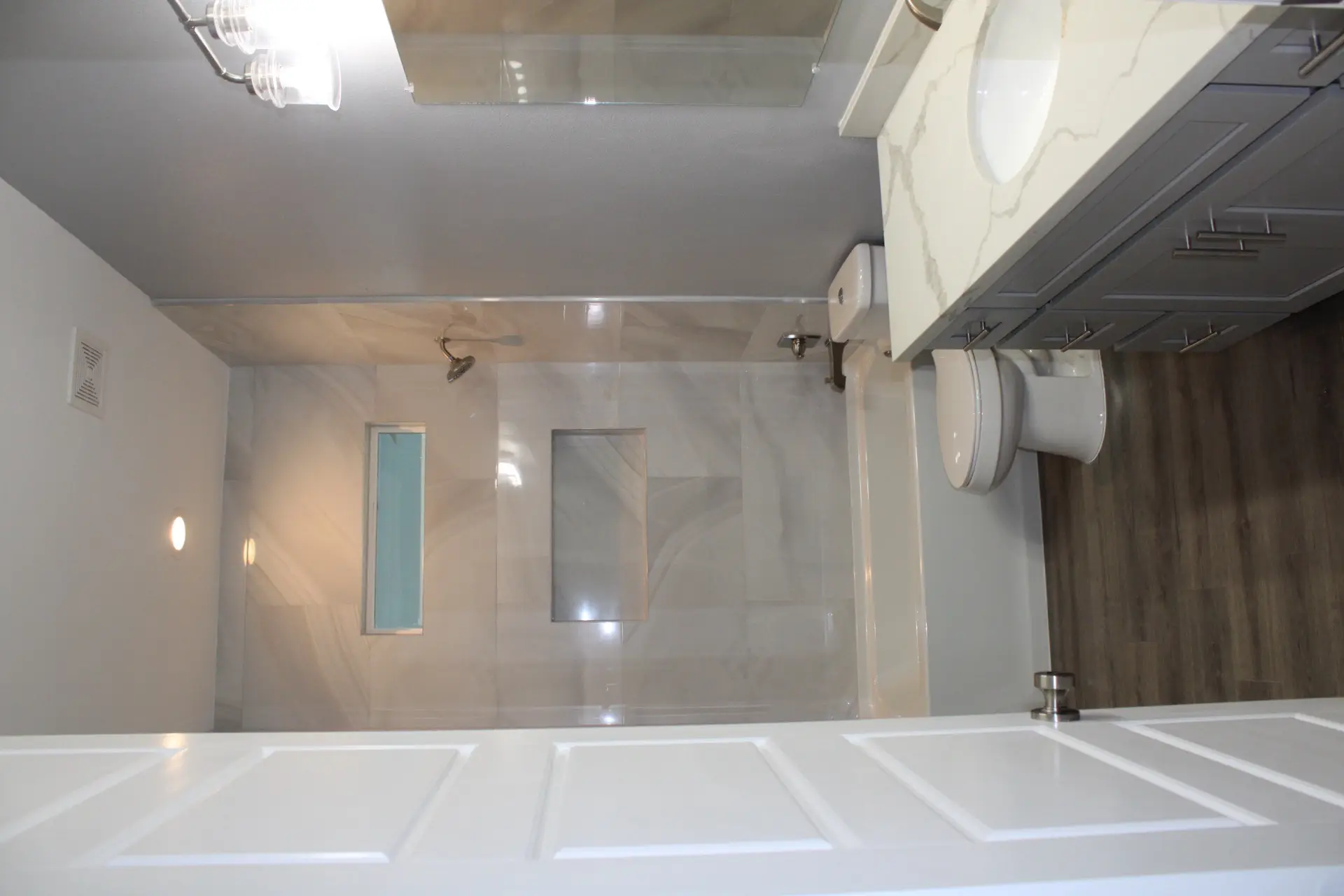 Side view of the classic beach house revealing the full wraparound porch extending along the blue exterior with white trim and railing
