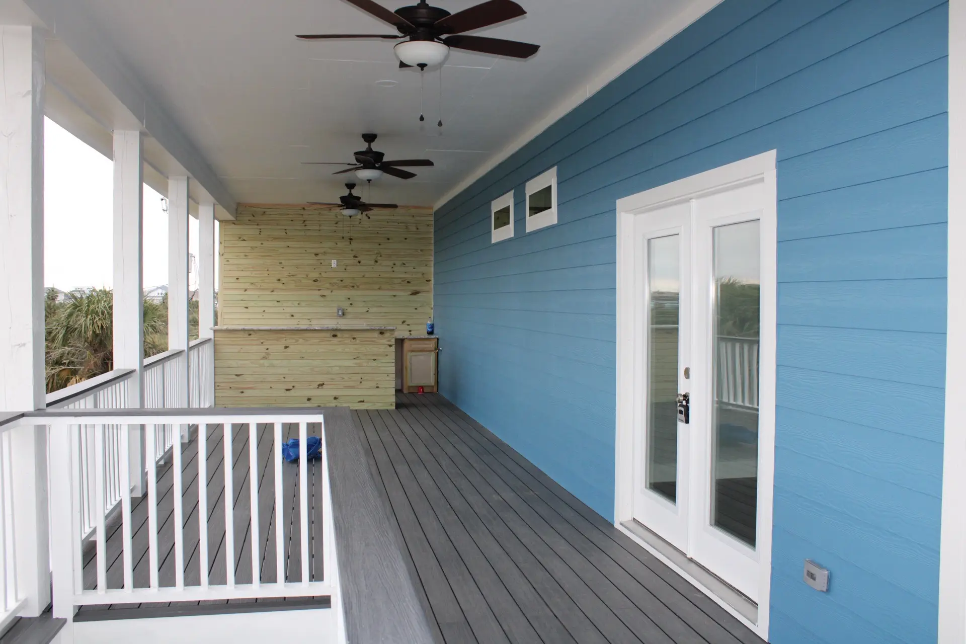 Full kitchen view from the living area showing the open layout, teal backsplash accent wall, pendant lights, and soft coastal color palette