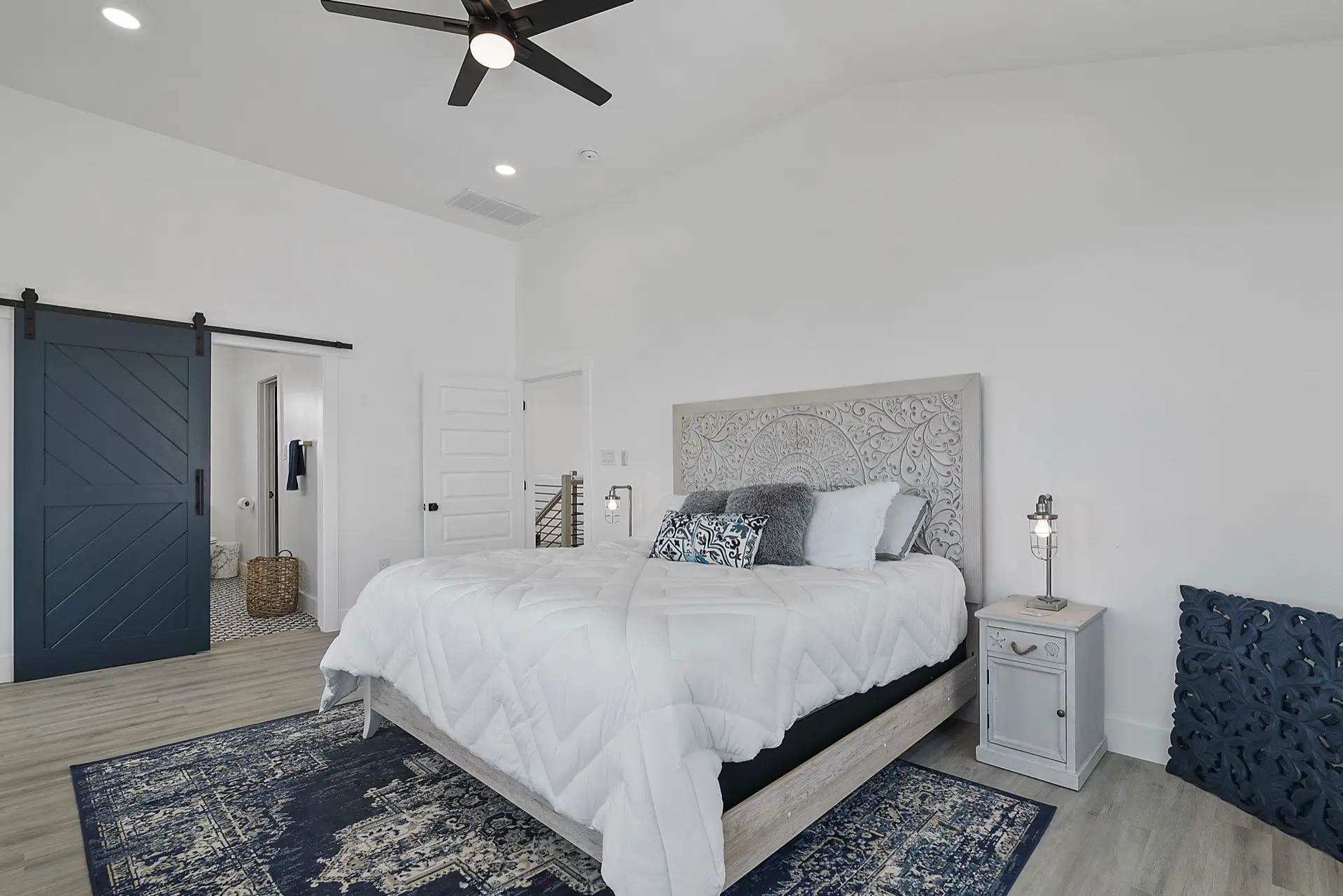 Living room seating area with neutral upholstered furniture, woven area rug, and canal views through the sliding glass doors to the covered deck
