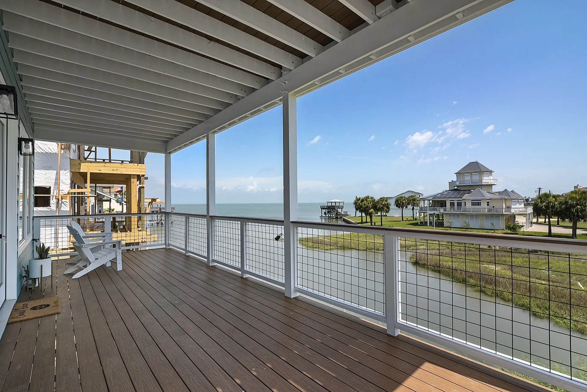 Expansive covered deck with composite decking, cable railing system, and panoramic canal and marsh views from the Tiki Island waterfront home