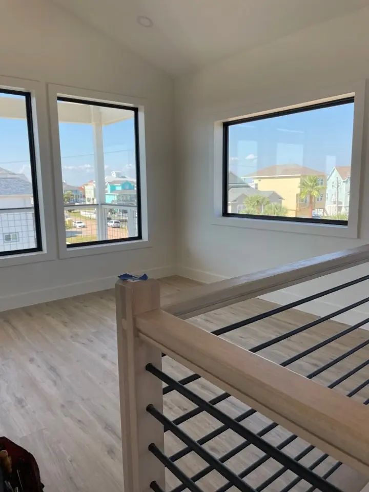 Secondary bathroom with coastal blue-green glass tile shower enclosure, brass shower fixtures and hardware, and frameless glass door