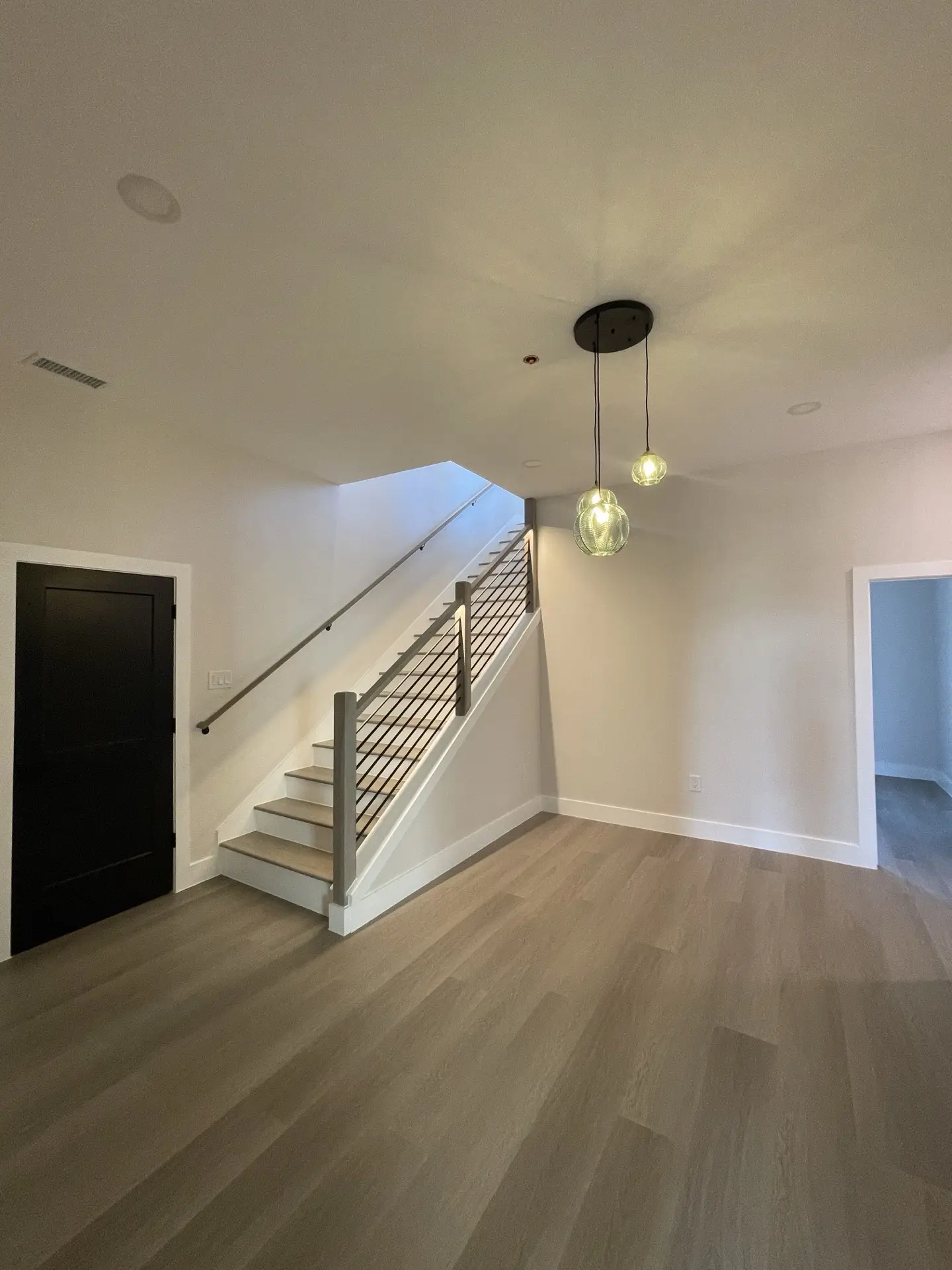 Sage green vanity bathroom with pebble mosaic floor tile, gold wall-mount faucet, and round designer mirror in the Blue Heron guest bath