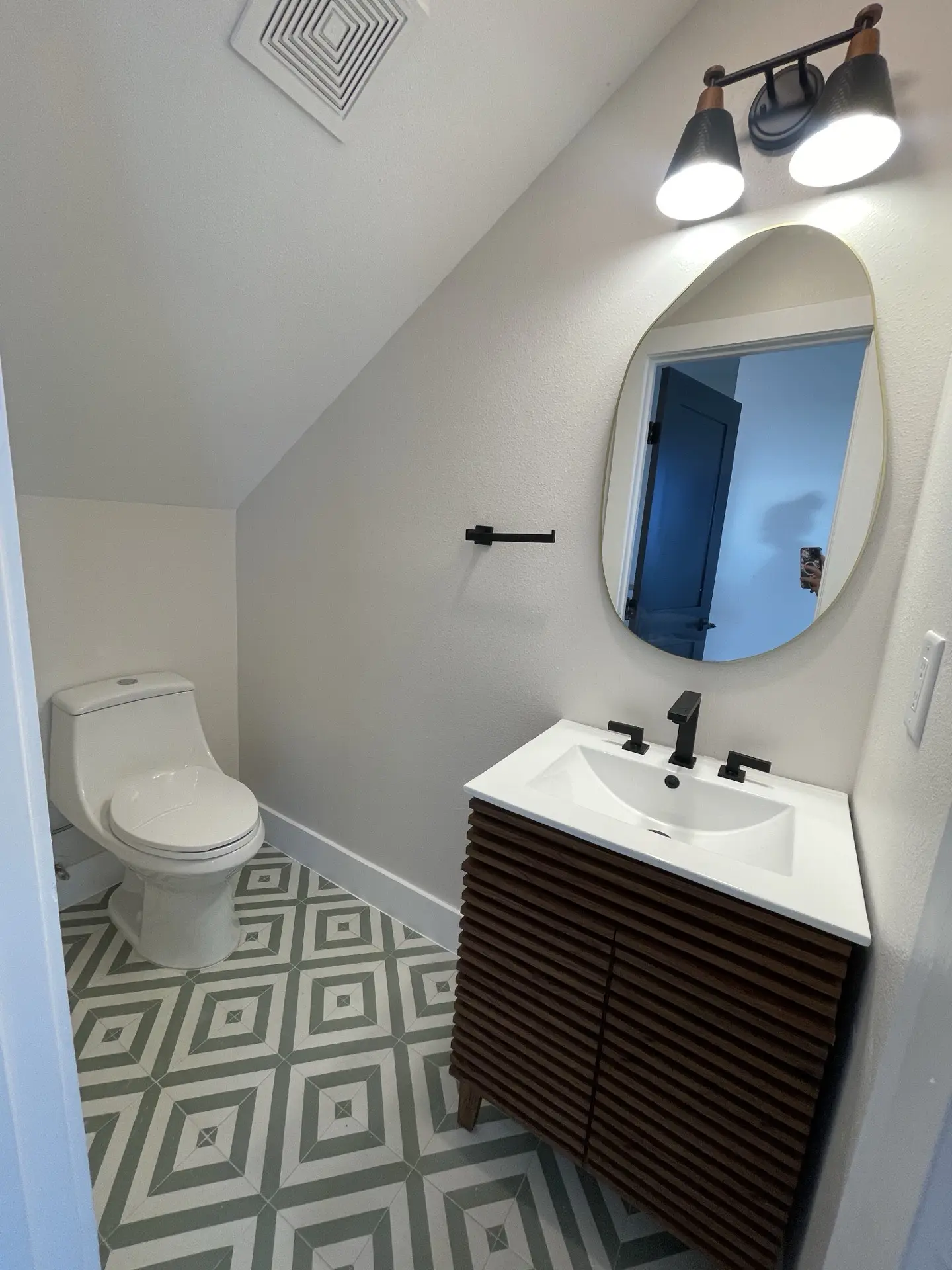 Bathroom detail showing artisan tile work, custom mirror, and luxury gold fixtures against a bold emerald green tile wall