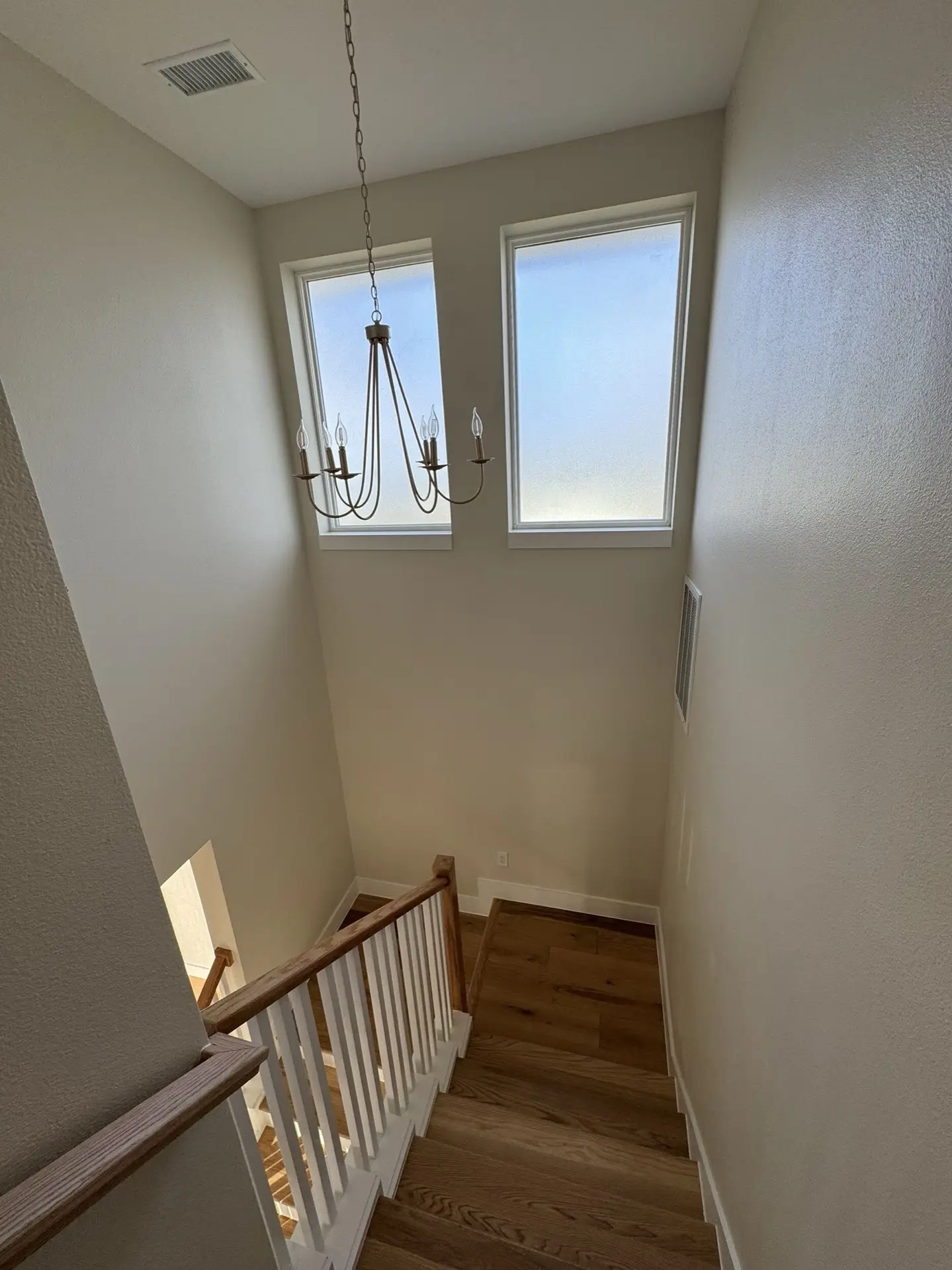 Living area with traditional Craftsman details including crown molding, wide-plank oak floors, and warm natural light from bay-facing windows