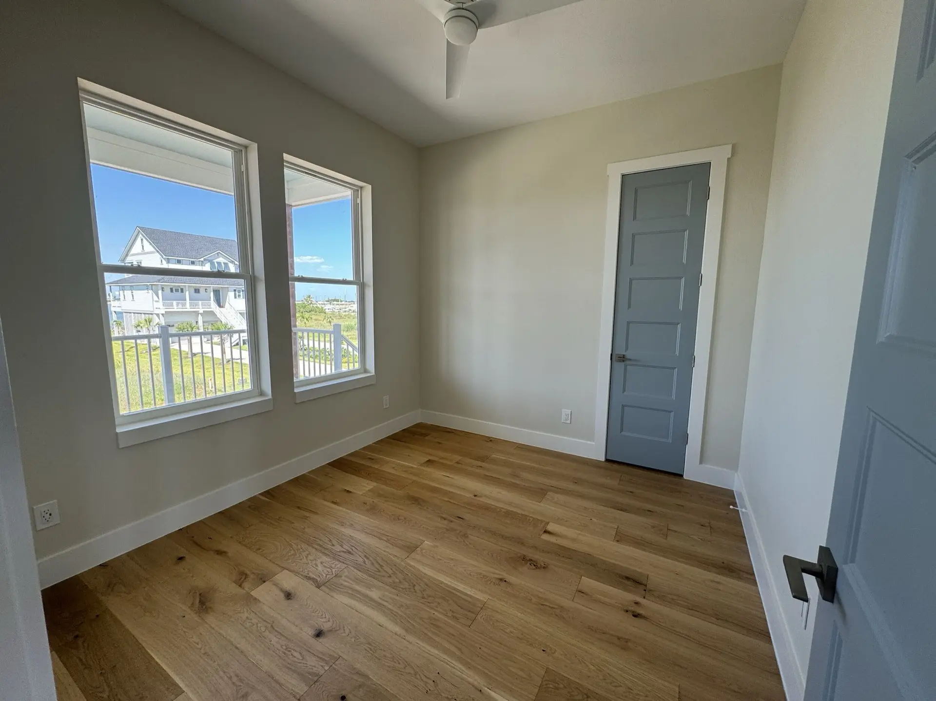 Sage green kitchen cabinets with brushed brass hardware, white countertops, and glass-front upper cabinet doors displaying dishware